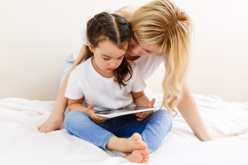 mother and baby are looking to play and read tablet computer on the couch at home