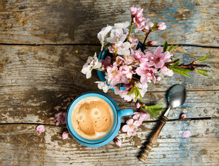 cup of Coffee with pink blooming flowers on grunge, old wood background top view. good morning post card, banner design 