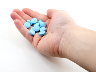 Male hand holding plue pills