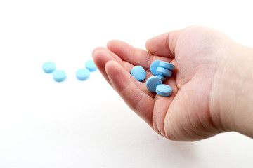 Male hand holding plue pills