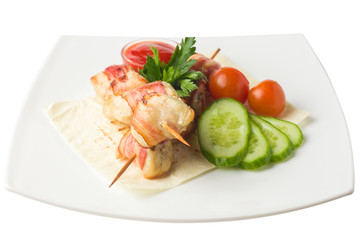 chicken on a skewer, baked in bacon, rests on a pita with cucumber, cherry tomatoes, parsley and savory sauce, white background, isolated