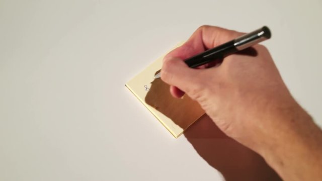 Person writing on stick note reminder telephone number