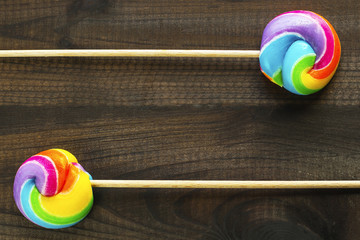 two rainbow colored lollipops on blue wooden background. Copy space. Top view.