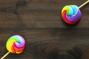 two rainbow colored lollipops on blue wooden background. Copy space. Top view.