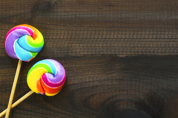 two rainbow colored lollipops on blue wooden background. Copy space. Top view.