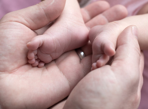 The legs of a newborn child in male hands