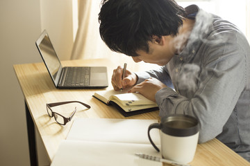 机の上で仕事・勉強をする男性