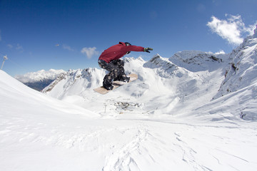 Naklejka na ściany i meble Snowboarder jumps in mountains, winter extreme sport.
