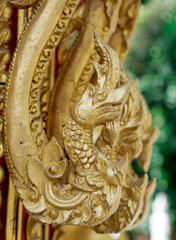 Wood carving is a golden serpent in Thai temple.
