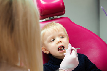 Dentist examining kid's teeth at dental clinic