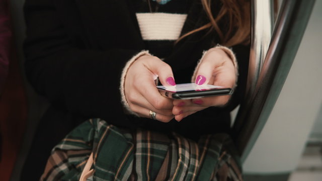 Close-up view of woman s hand holding a smartphone, sitting in public transport. Girl uses touchscreen technology. - Powered by Adobe