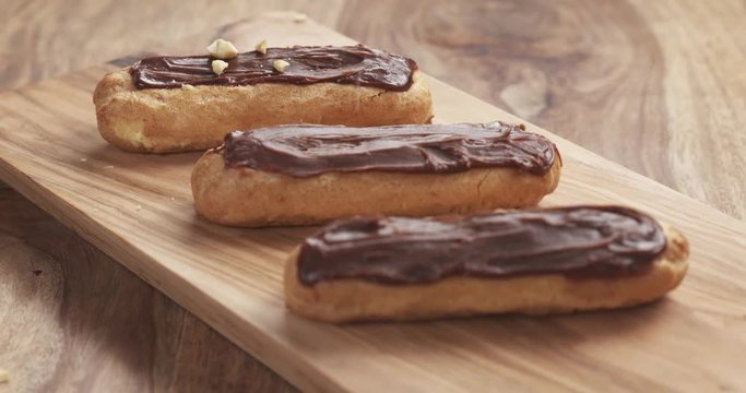 Slow motion of decorating eclairs with hazelnuts on wood board, 4k 60fps prores footage