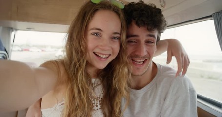 Portrait of teenage couple taking selfie photograph kissing smiling laughing in retro campervan on summer road trip adventure pov - Powered by Adobe