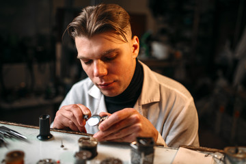 Watchmaker repair broken clockwork with tweezers