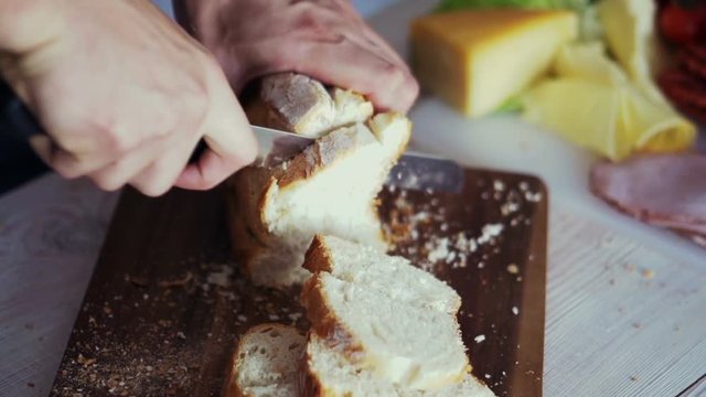 Male hand slicing bread, super slow motion 
