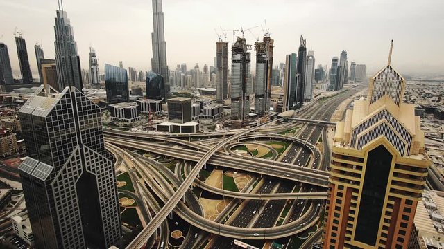 Spectacular daytime skyline of downtown Dubai, UAE. Scenic aerial view of famous highway intersection at sunset. Transportation and travel background. 4K time lapse.