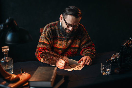 Bearded writer in glasses writes with a feather