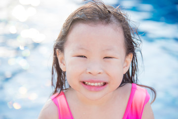 Little asian girl smiles at swimming pool