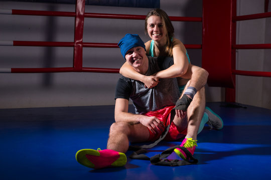 Athletic woman support and hug her boyfriend in a boxing ring