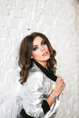 Fototapeta premium Fashionable young beautiful woman posing in a silver jacket.