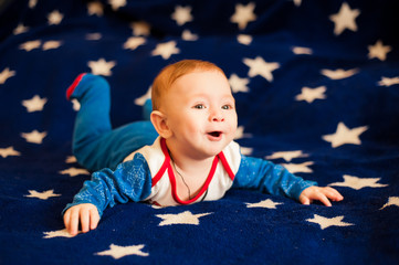 Child 6 months old and smiling at home on a blue blanket of the starry sky