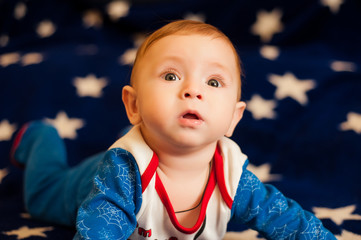 Child 6 months old and smiling at home on a blue blanket of the starry sky