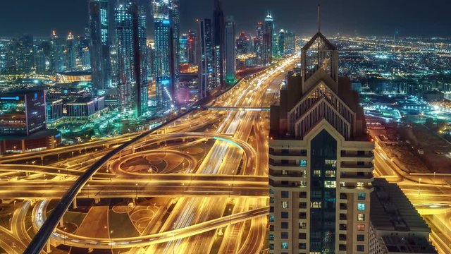 Spectacular nighttime skyline of downtown Dubai. Scenic aerial view of big highway intersection and skyscrapers. 4K time lapse.