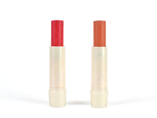 Open sticks of a red color and a nude color lip balm on white background