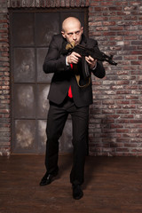 Assassin in suit and red tie holding machine gun