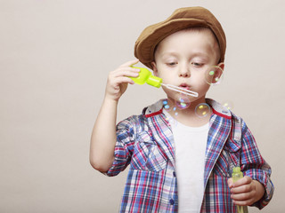 Little cute boy is blowing soap banks