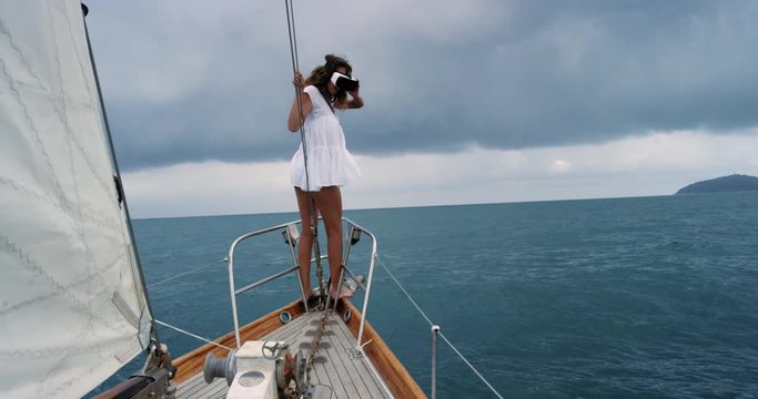 Brave Young Woman at front of sailboat wearing virtual reality headset watching storm 360 video climate change imagination concept