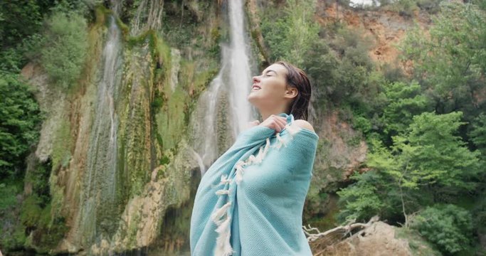 Young woman drying off with towel wild swimming in natural pond at base of hidden waterfall Best friends girls in nature enjoying carefree vacation outdoors adventure