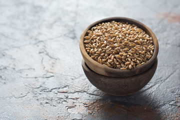 Spelt in a wooden bowl on the grey background
