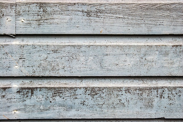 Old and weathered blue painted wood siding with flaking paint