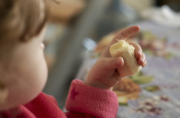 A little girl eats a slice of banana