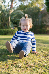 Naklejka na ściany i meble small baby boy with happy face on green grass barefoot