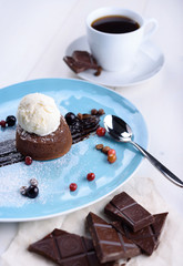 Chocolate fondant with ice cream, pieces of chocolate and coffee on a white table