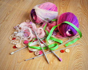 Skeins of thread, buttons and measuring tape on wooden background. 