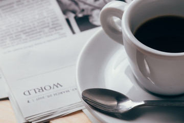 Cup of coffee with newspaper in background