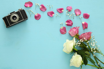 Top view of old camera and roses over wooden table