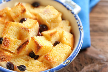 Bowl with delicious bread pudding on table, closeup