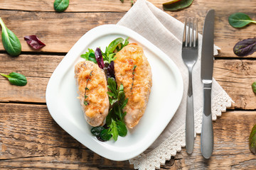 Plate with delicious chicken breasts on wooden table