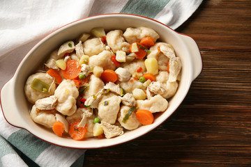 Baking dish with delicious chicken and dumplings on wooden table