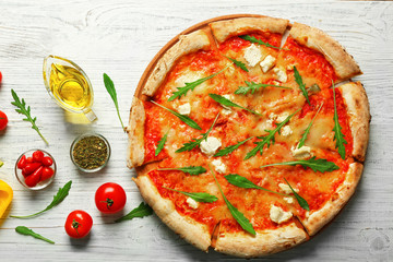 Delicious pizza with ingredients on wooden table