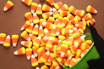 Bucket and tasty Halloween candies on color background