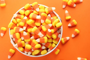 Bucket with tasty Halloween candies on color background, closeup