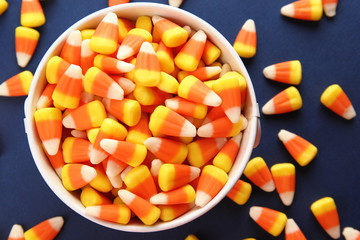 Bucket with tasty Halloween candies on color background, closeup