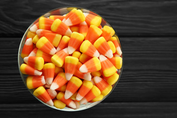 Bowl with tasty Halloween candies on dark wooden background, closeup