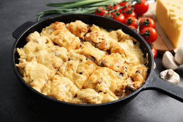 Roasted chicken with cheese in frying pan on kitchen table