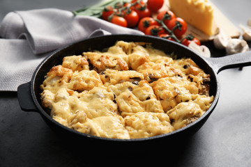 Roasted chicken with cheese in frying pan on kitchen table